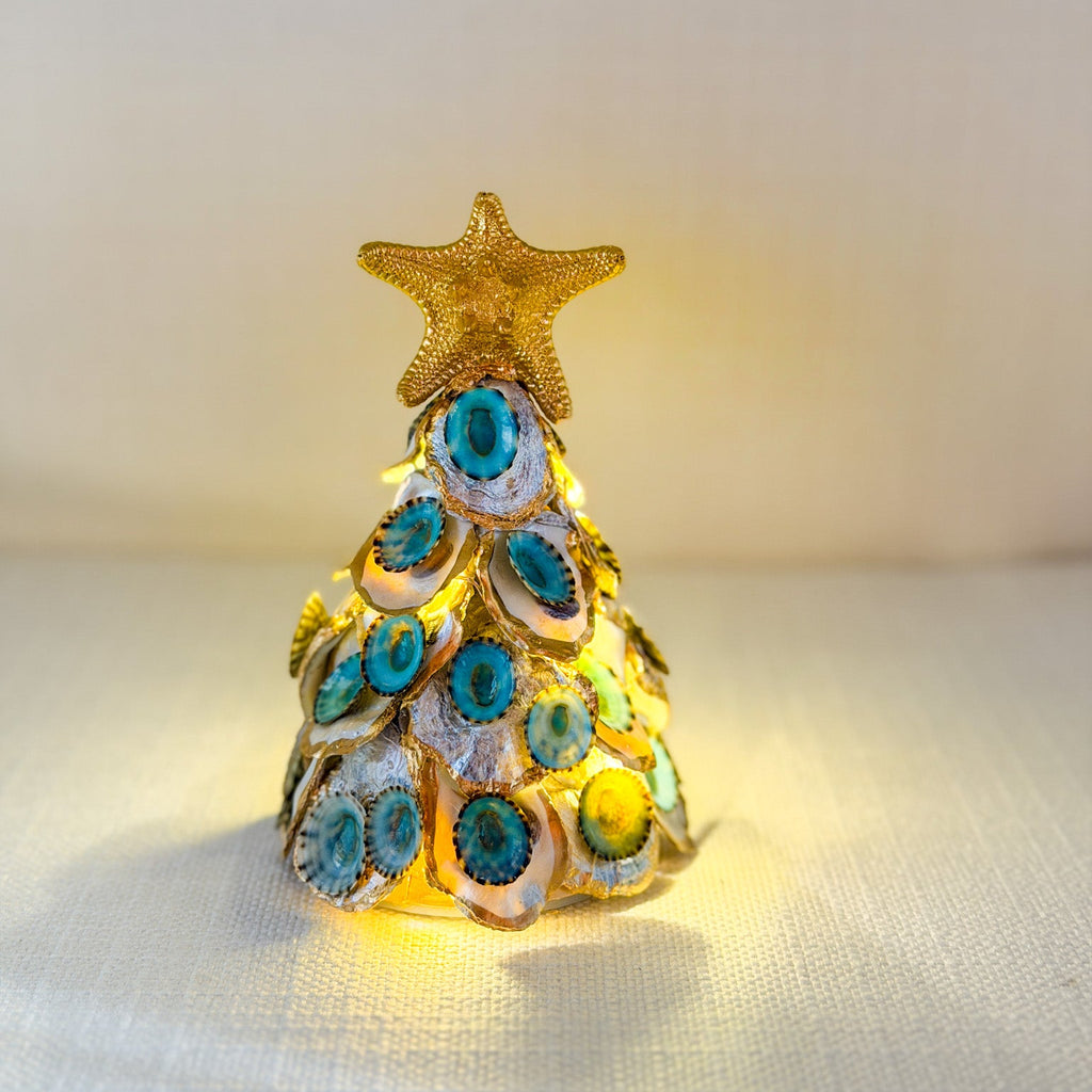 Decorative 6" Christmas tree with blue limpets and gold trim on a pearl oyster shells