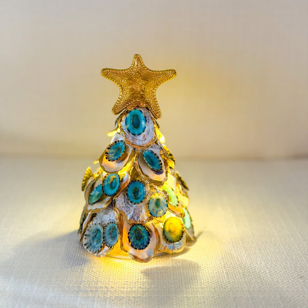 Decorative 6" Christmas tree with blue limpets and gold trim on a pearl oyster shells